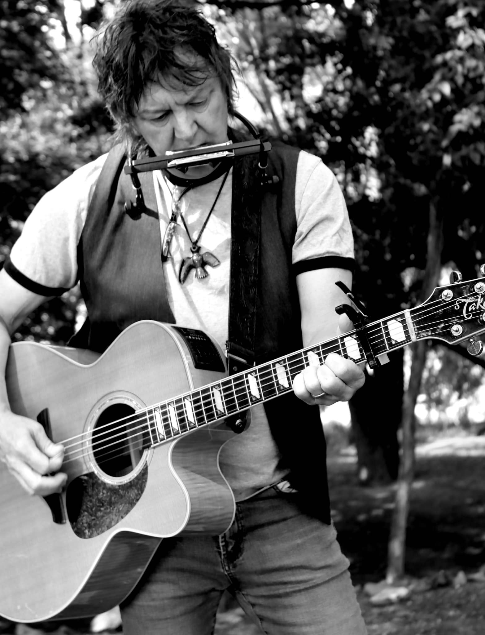 Rusty Bladen playing the harmonica and guitar